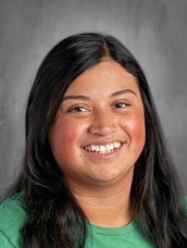 Smiling young woman with long black hair, wearing a green shirt, against a gray background.